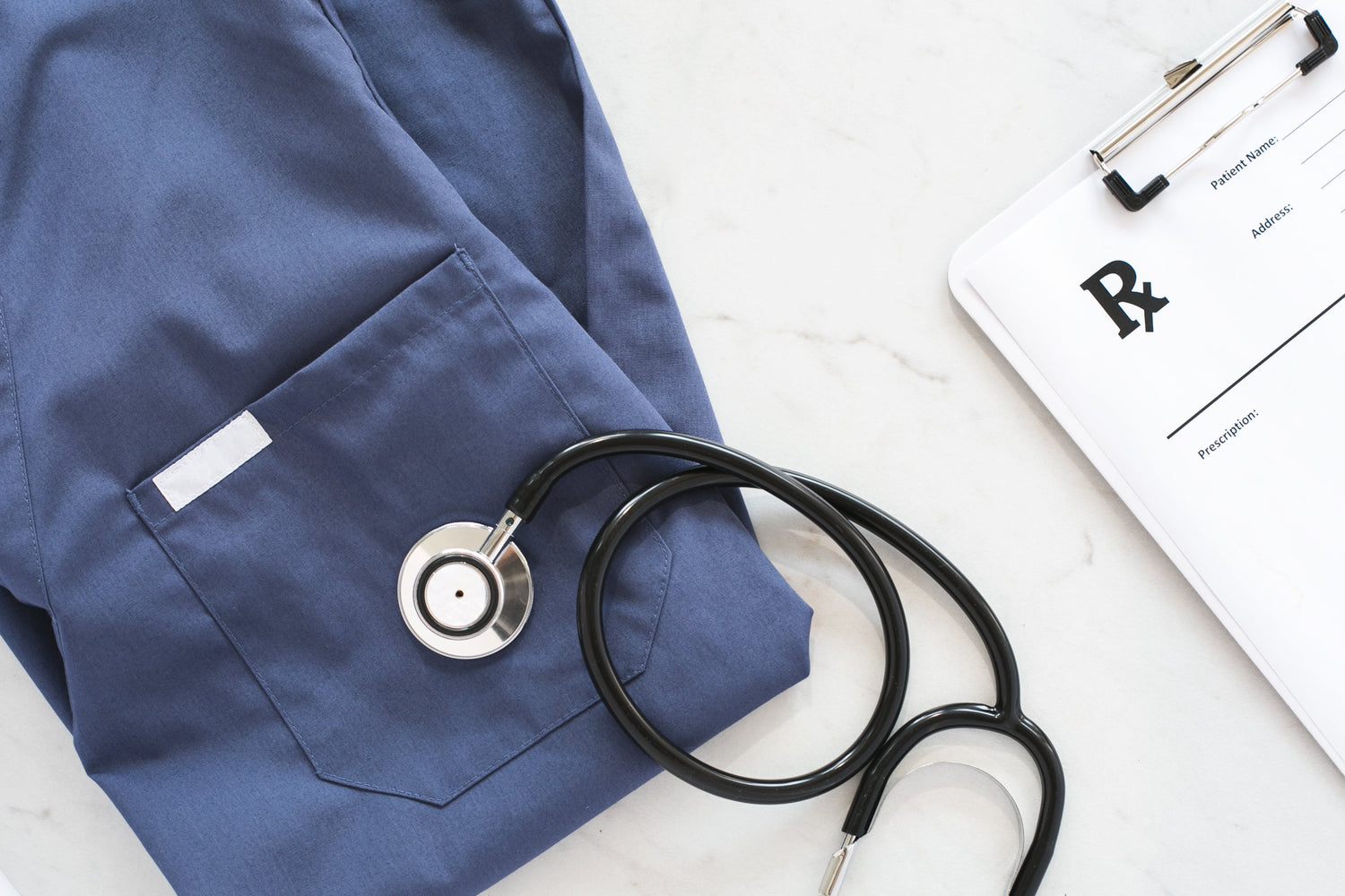 Blue medical coat with stethoscope and clipboard on a white surface
